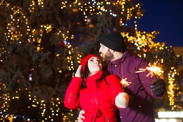 couple in winter attire with Christmas lights around