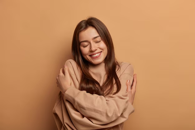 Woman smiling while hugging herself